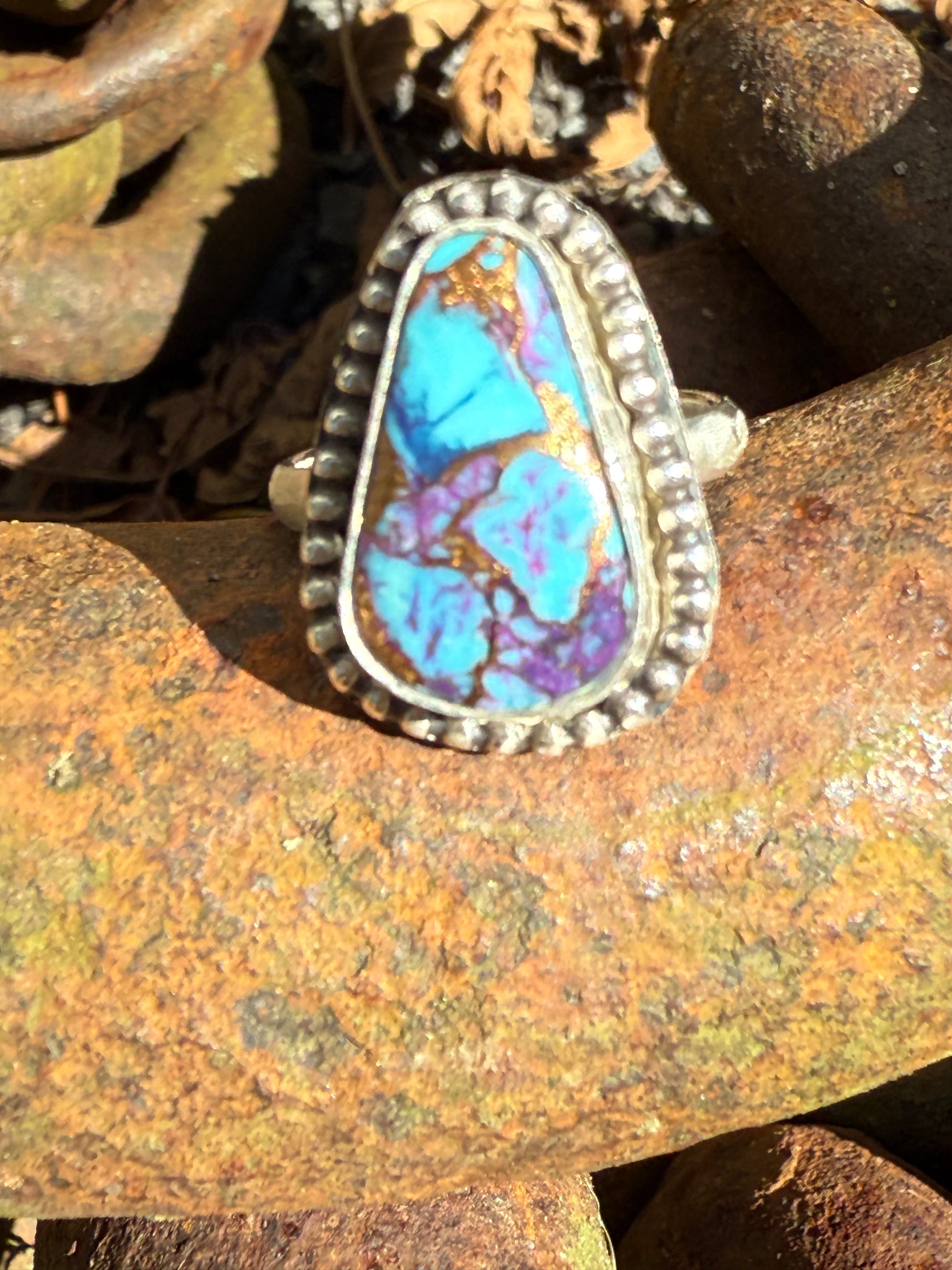 Silver ring with a turquoise stone on a rusty metal surface