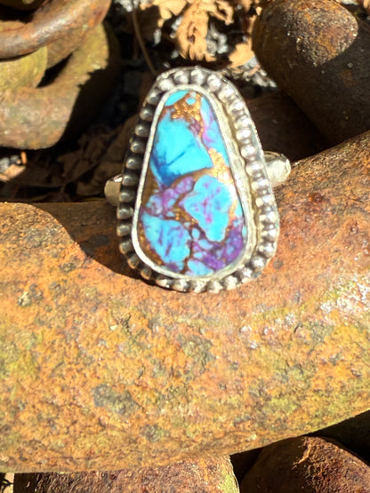 Silver ring with a turquoise stone on a rusty metal surface