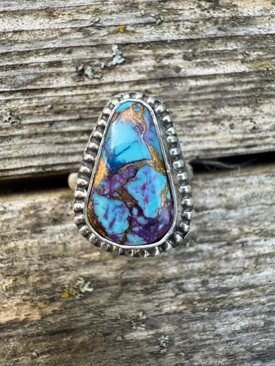 Ring with a colorful stone on a wooden surface